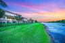 Waterfront property featuring a stucco exterior, a tile roof, an expansive lawn, and a black metal fence