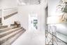 Two-story entry featuring white walls, a carpeted staircase with white balusters, and polished tile flooring