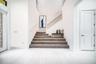 Spacious foyer with light-toned flooring and a white paneled door
