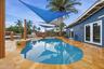 Freeform pool with a spa, surrounded by natural stone tile paving