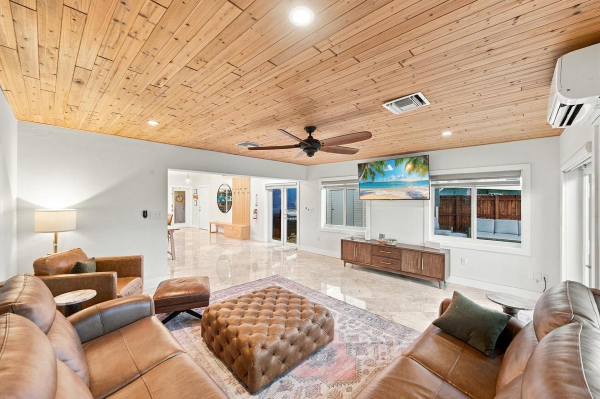 Wood-paneled ceiling, recessed lighting, ceiling fan, polished tile flooring, and multiple windows