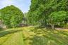 Expansive lawn surrounded by mature trees, providing a spacious outdoor setting