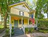 Victorian-style exterior with yellow siding, covered front porch, decorative gable trim, and a brick paver walkway