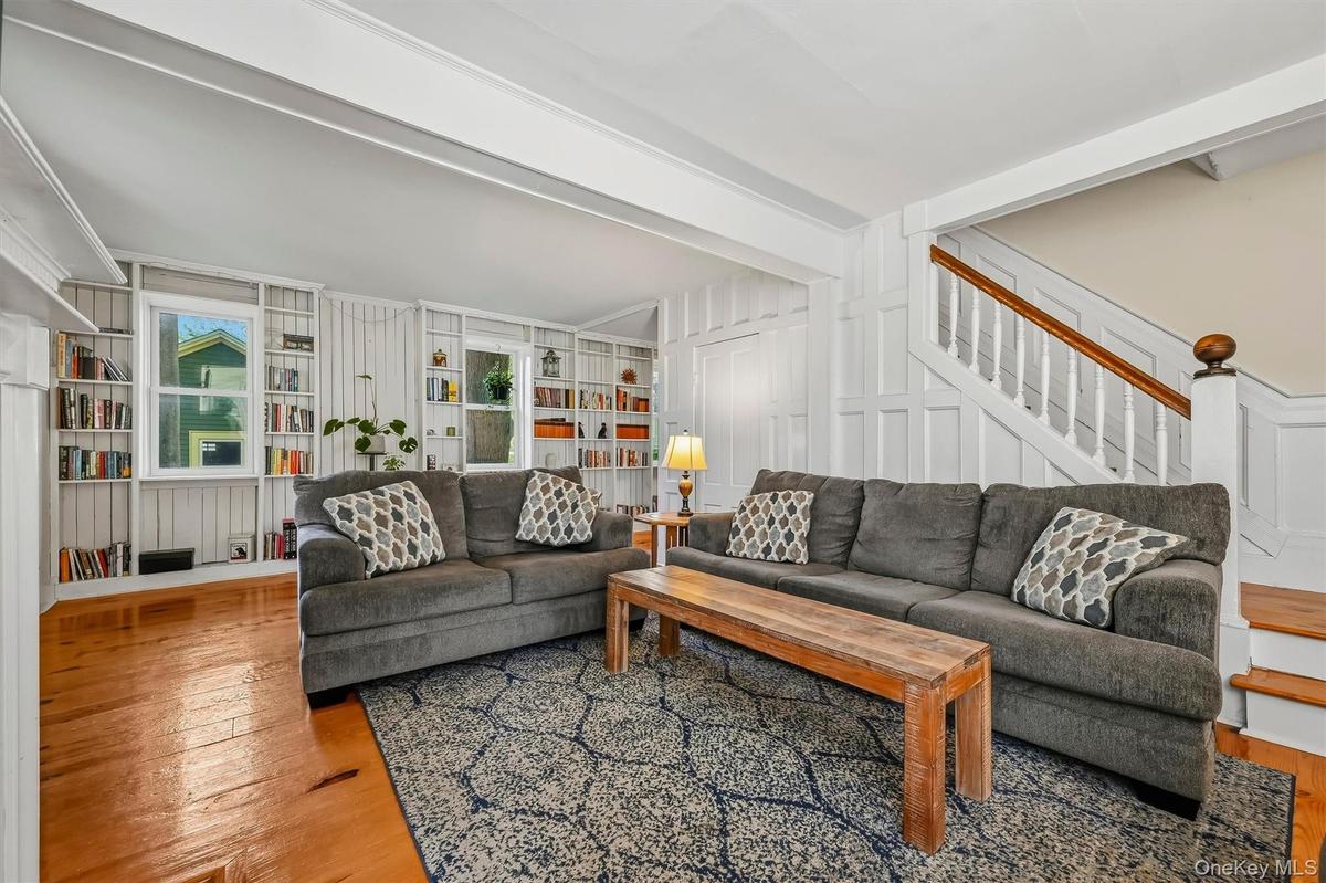 Spacious living room with wood floors, built-in bookshelves and staircase access