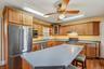 Kitchen featuring wood cabinetry, stainless steel appliances, a center island with countertop seating, and wood-finish flooring