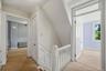 Carpeted hallway with white painted balusters and railings, featuring two paneled doors and a window with white trim