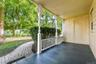 Covered porch with decorative columns, painted wood flooring, and paneling along the exterior wall