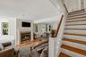 Hardwood flooring, brick fireplace with a white mantel, white trim, recessed lighting, and a detailed staircase with a wood handrail