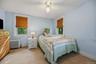 Bright bedroom with multiple windows, ceiling fan, and classic trim