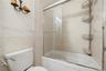 Unit 2 - Bathroom tub and glass enclosure, alternate view. Digitally decluttered.