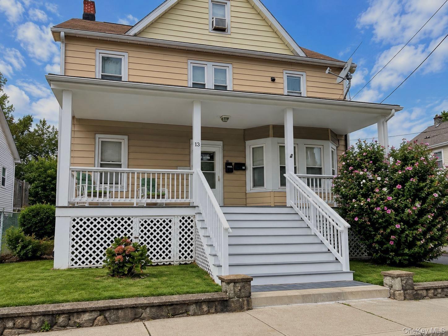Two-story residence with a covered front porch featuring white railings