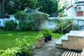 Expansive green lawn, established landscaping, privacy fencing, concrete patio, and brick steps with a metal handrail