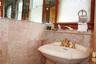 1st floor bathroom with pedestal sink with gold-finish faucet, full-width mirror, and marble tiles.