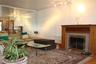 Living room has wood-finish flooring with a  working fireplace featuring a wood mantel and stone surround, and a wall of mirrored panels