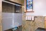 2nd floor bathroom has glass-enclosed shower with frosted panel, natural stone wall finishes, and a stained-glass window accent