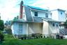 Manicured lawn, brick chimney, multiple windows, solar panels, and a rear entry door