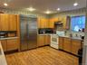 Kitchen with stainless steel appliances, light countertops, light wood-style flooring, under cabinet range hood, and backsplash
