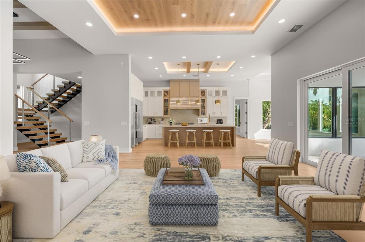 Virtually staged family room featuring a custom inlaid wood ceiling, flowing seamlessly into the kitchen and dining area.