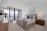 A serene primary suite with private balcony access and sunrise views over the bay.