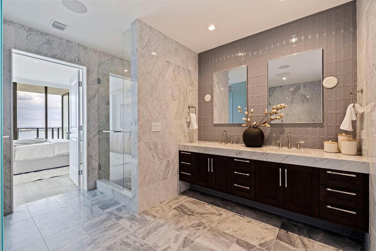 A serene primary bath where sculptural finishes, rich marble, and spa-like details create a true private retreat.
