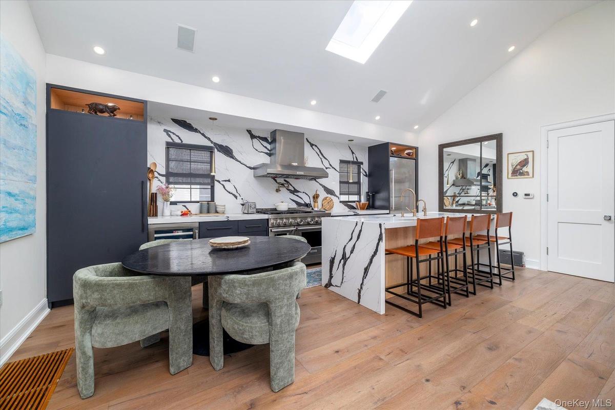 Large kitchen with stainless steel appliances, a large island with seating for 4 and a separate dining table