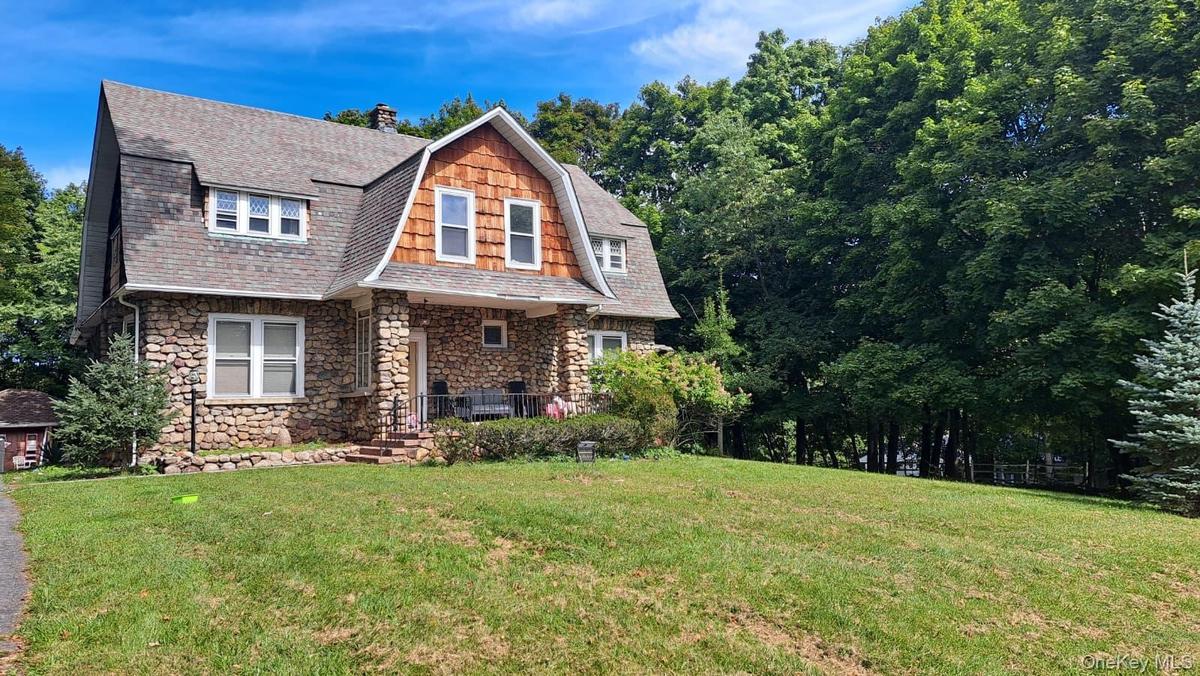 Stone veneer exterior with cedar shake accents, a gable roofline, and a covered front porch