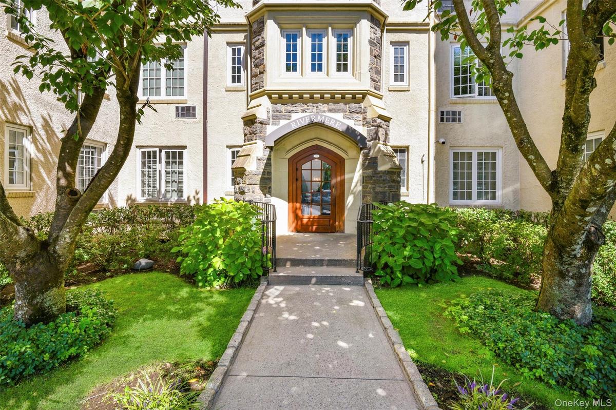 Property entrance featuring stone siding, a gate, stucco siding, and a lawn