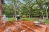 Expansive wooden deck with natural wood siding, leading to a manicured lawn framed by mature trees