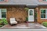 Wood-shingle exterior with white trim windows and a white arched-pane door