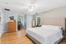 Hardwood flooring throughout, a white ceiling fan, and multiple windows providing natural light