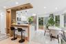 Modern kitchen featuring white cabinetry, stainless steel appliances, a breakfast bar with pendant lighting, a sliding glass door, and a dining area w
