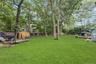 Expansive backyard featuring a manicured lawn, mature trees, and a wooden deck