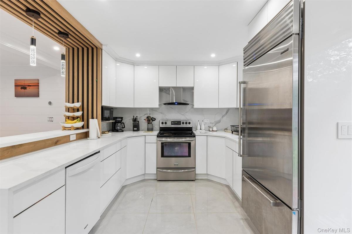 Modern kitchen featuring white glossy cabinetry, stainless steel appliances, a white countertop, and recessed lighting