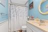 White paneled wainscoting with a light blue wall, a built-in vanity with a single basin, and a wall-mounted oval mirror
