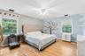 Hardwood flooring, two windows with natural light, ceiling fan with light fixture, and painted walls
