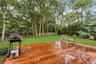 Spacious wood-finish deck with a manicured lawn and mature trees