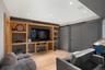 Recessed lighting, wood-finish flooring, built-in media console with shelving, and sliding barn doors with matte black hardware