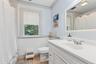 White vanity with a single basin sink, chrome faucet, and integrated countertop