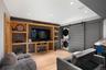Built-in entertainment center with open shelving, light wood-finish flooring, recessed lighting, and a barn door concealing stacked laundry appliances
