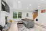 Recessed lighting, wood-finish flooring, a white-painted fireplace with a stone hearth, a multi-pane entry door, and a natural wood staircase with a b