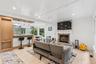 Open-concept living area featuring a stone-clad fireplace, light wood-finish flooring, recessed lighting, and a white shiplap ceiling
