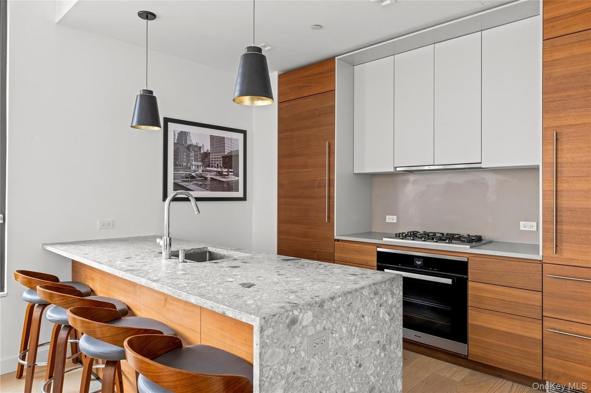 Kitchen featuring brown cabinets, modern cabinets, a peninsula, black oven, and a breakfast bar area