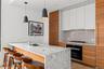 Kitchen featuring brown cabinets, modern cabinets, a peninsula, black oven, and a breakfast bar area