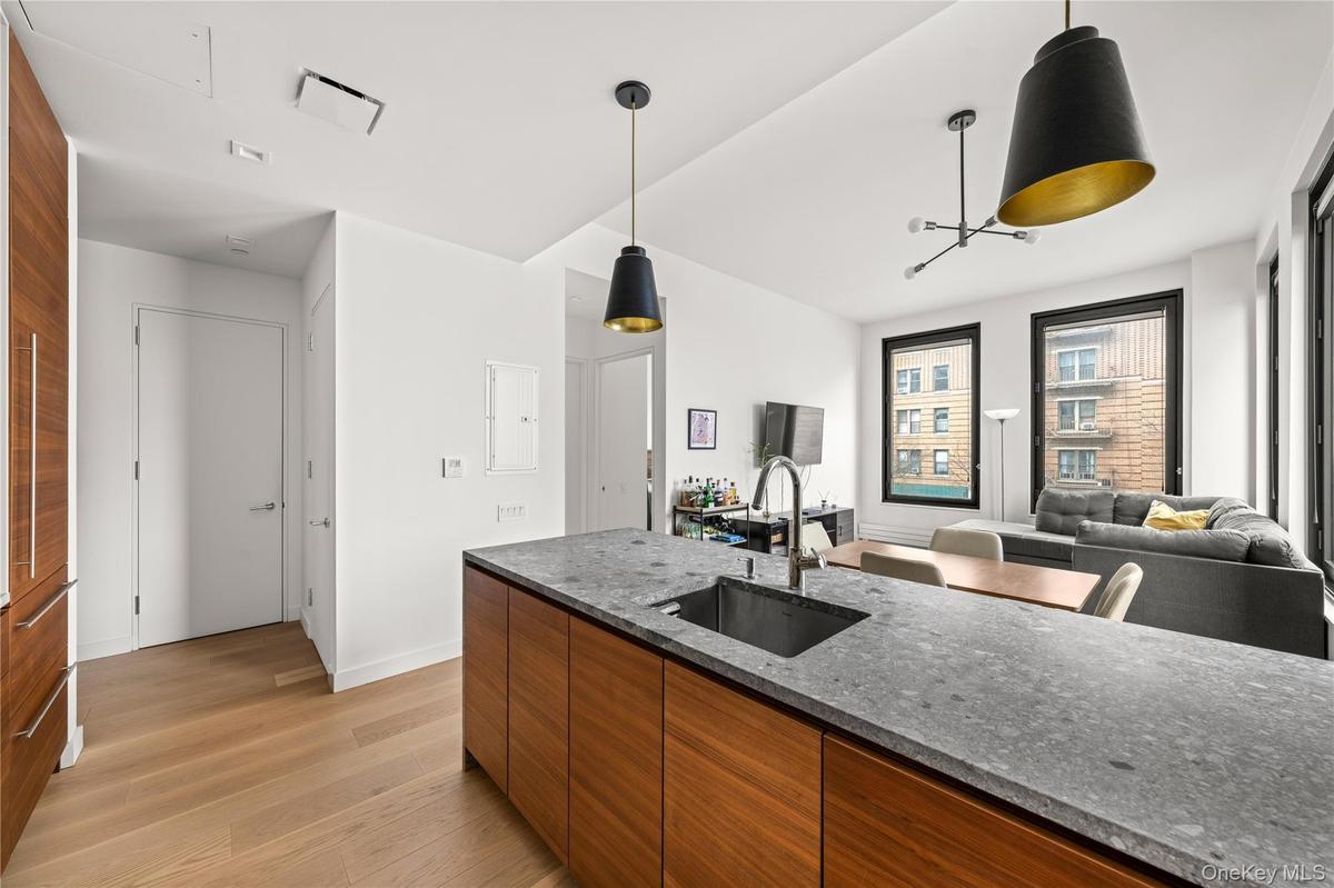 Kitchen with brown cabinetry, dark stone counters, hanging light fixtures, open floor plan, and modern cabinets