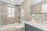 Bathroom with bathing tub / shower combination, tile walls, vanity, and ornamental molding