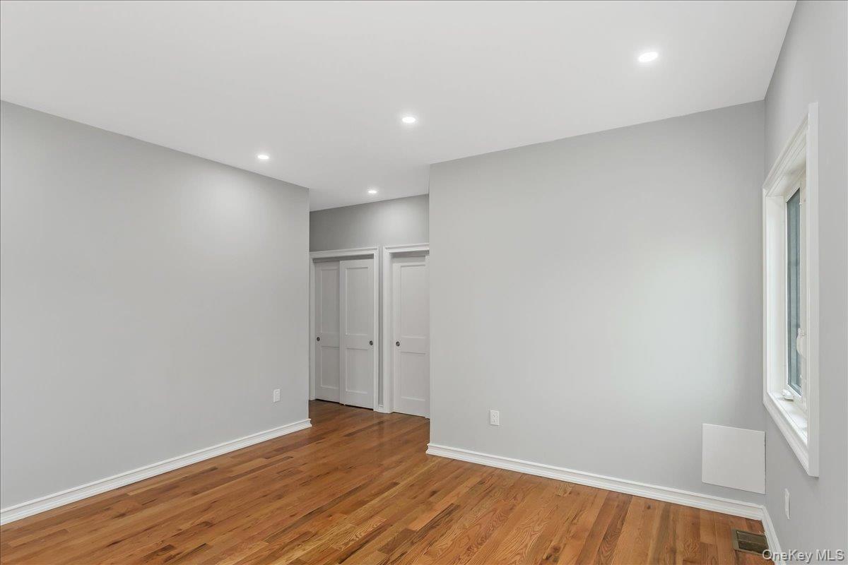 Unfurnished bedroom featuring wood finished floors, recessed lighting, and multiple closets