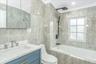 Full bath with tile walls, tiled shower / bath combo, vanity, and crown molding