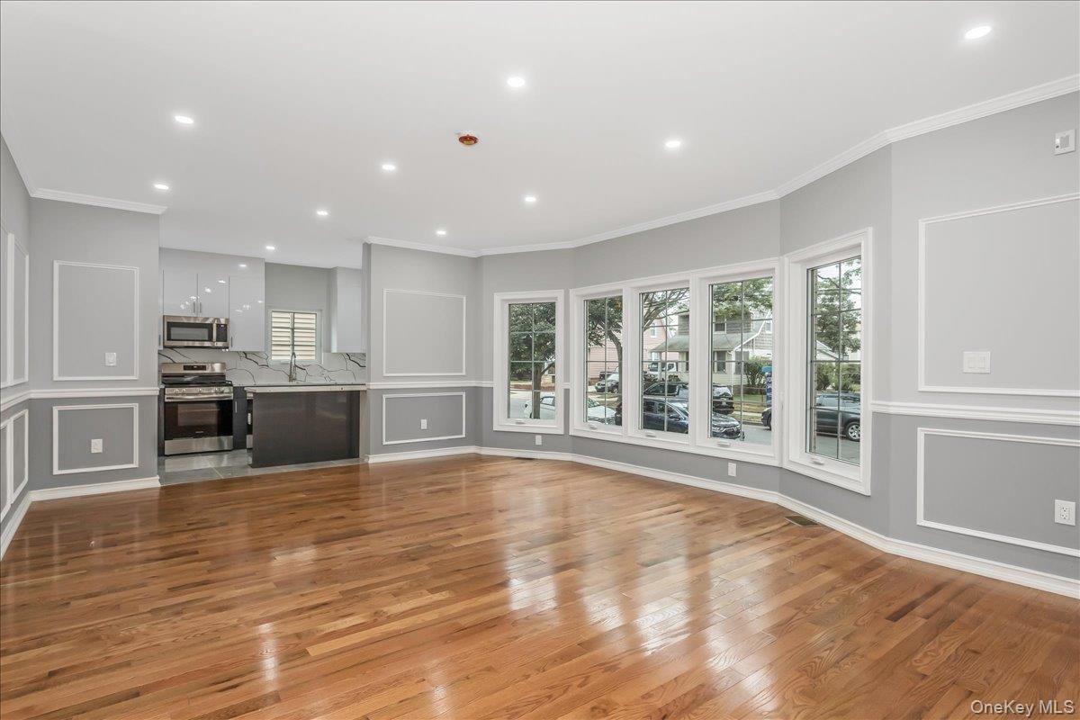 Unfurnished living room with crown molding, a decorative wall, light wood-style floors, and recessed lighting