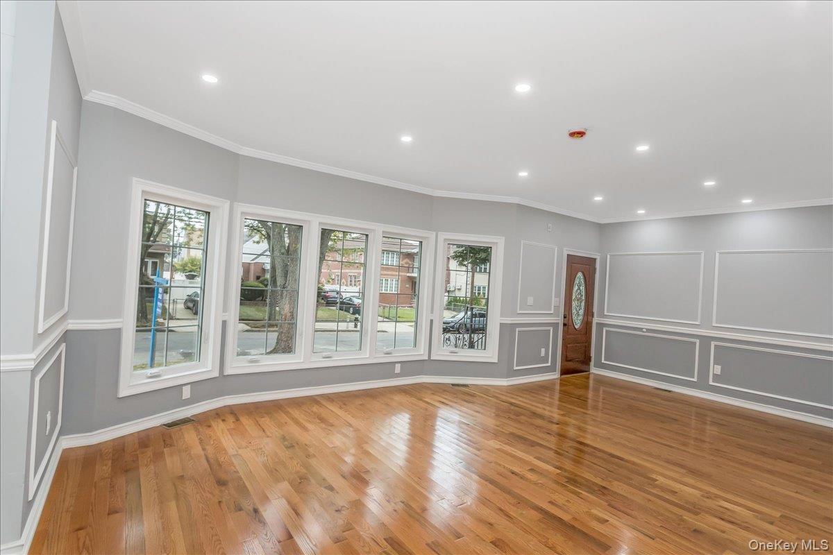 Unfurnished living room featuring crown molding, light wood finished floors, recessed lighting, and a decorative wall