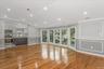 Unfurnished living room featuring plenty of natural light, light wood finished floors, a decorative wall, ornamental molding, and vaulted ceiling